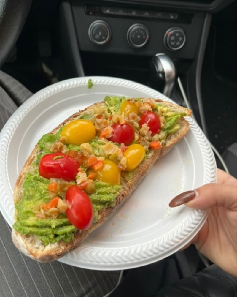 Tartine à l'avocat garnie d'antipasto Chuck Hughes et de tomates cerises, tenue dans une voiture
